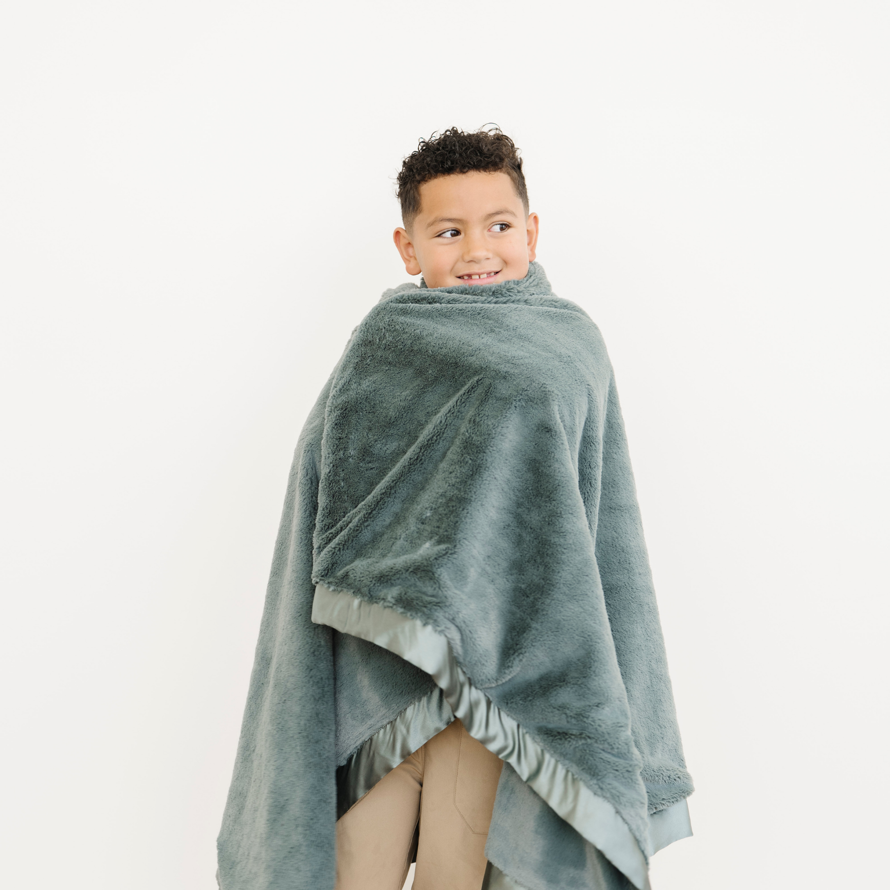 Boy wrapped in Evergreen Satin Border Lush Toddler Blanket. 