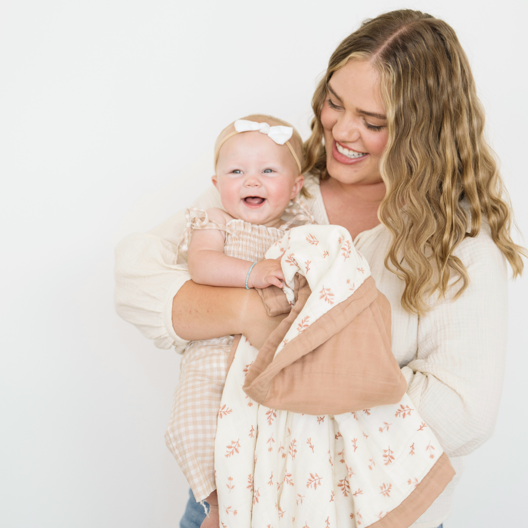 Mom holding baby girl with Floret Bamboo Rayon Muslin 4-Layer quilt. 