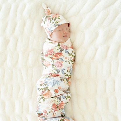 Baby girl swaddled in Vintage Floral Saranoni soft stretchy swaddle with a matching hat.