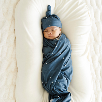 Baby boy sleeping, swaddled in Saranoni soft Stretchy Swaddle in Denim Triangle print.