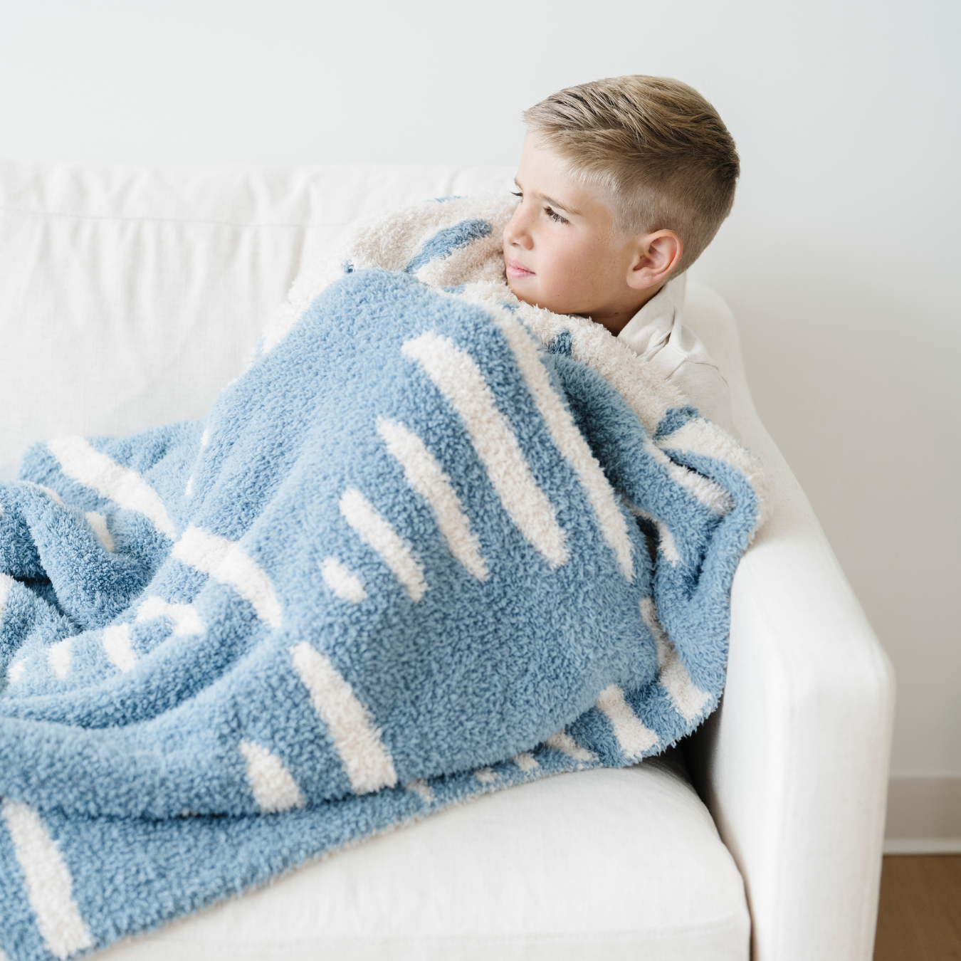 Boy snuggles with triangle double layer bamboni toddler blanket.