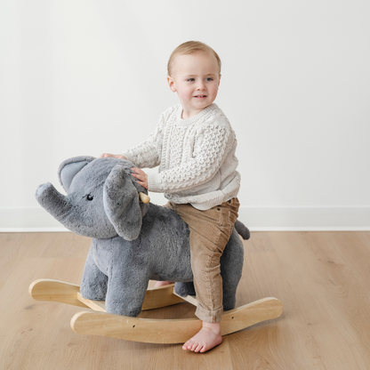A little boy is sitting on a gray elephant stuffed animal rocker. This kid's rocker is an adorable addition to a playroom, nursery, or bedroom. 