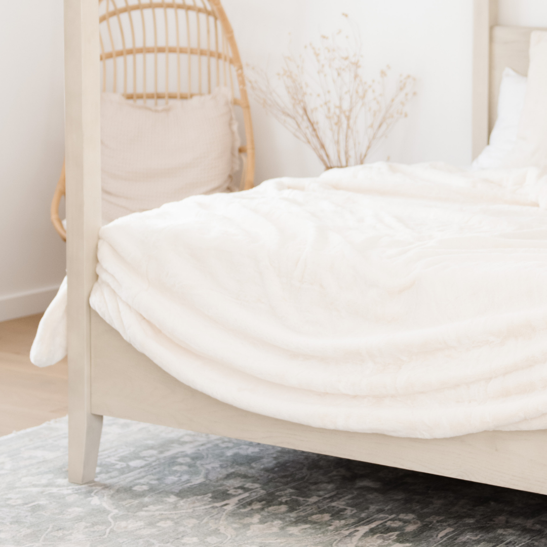 Draped on a bed is a Saranoni Grand Faux Fur blanket, featuring an elegant white tone and luxuriously soft texture. This cozy, queen-sized blanket and faux fur blanket offers soothing weight, premium softness, timeless comfort, and is a soft blanket. Perfect as a big blanket and luxury blanket for snuggling or as a luxury bedroom accent, this Saranoni blanket elevates every cozy moment and is a cozy blanket.