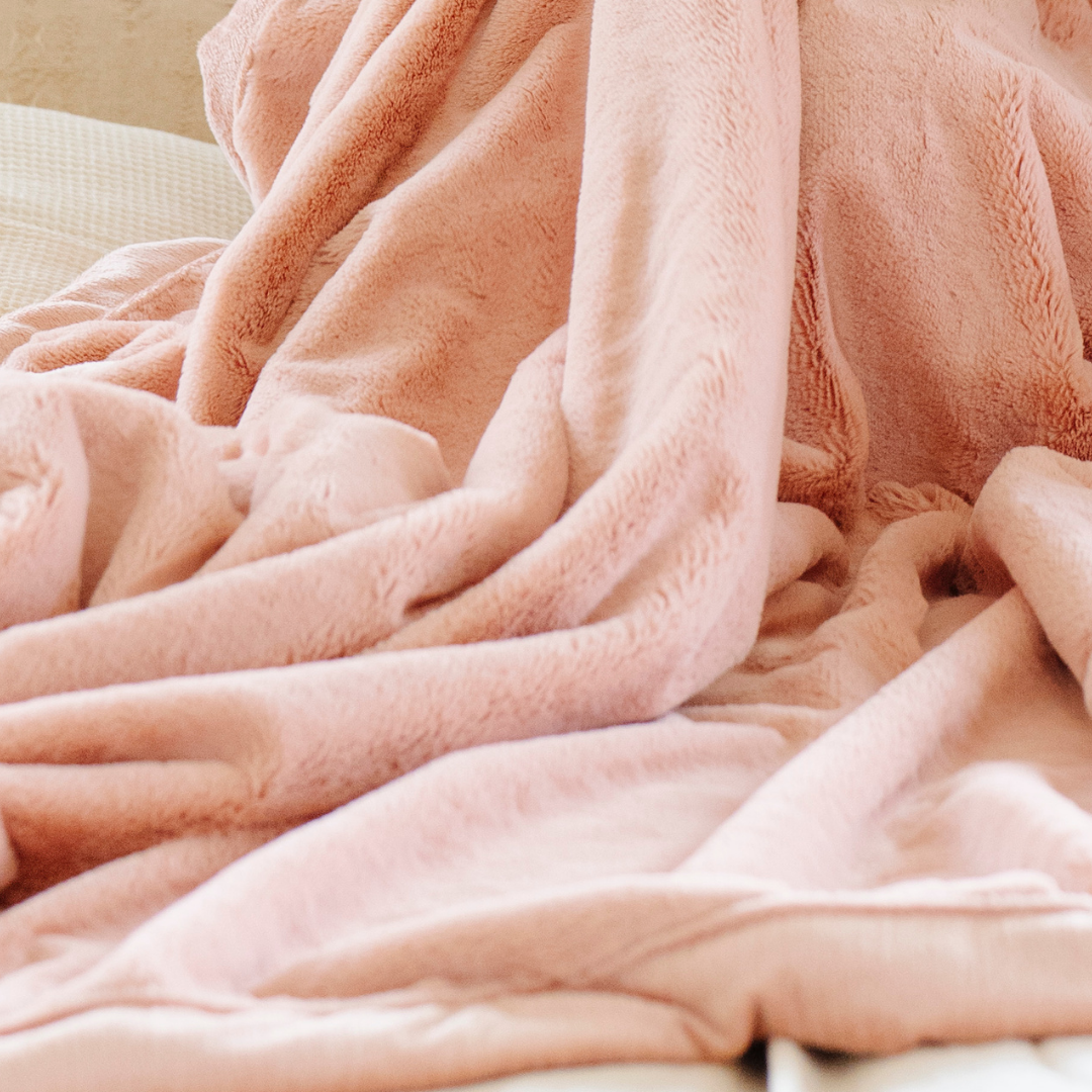 A Blossom (light peach/pink) Lush XL Saranoni blanket, designed for oversized comfort and featuring a buttery soft, plush texture. This luxurious Saranoni blanket is perfect for cozy evenings, reading, or home decor. The Saranoni blanket adds warmth, style, and unmatched softness, making it an ideal gift or essential for ultimate relaxation.