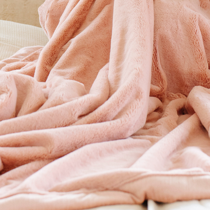 A Blossom (light peach/pink) Lush XL Saranoni blanket, designed for oversized comfort and featuring a buttery soft, plush texture. This luxurious Saranoni blanket is perfect for cozy evenings, reading, or home decor. The Saranoni blanket adds warmth, style, and unmatched softness, making it an ideal gift or essential for ultimate relaxation.
