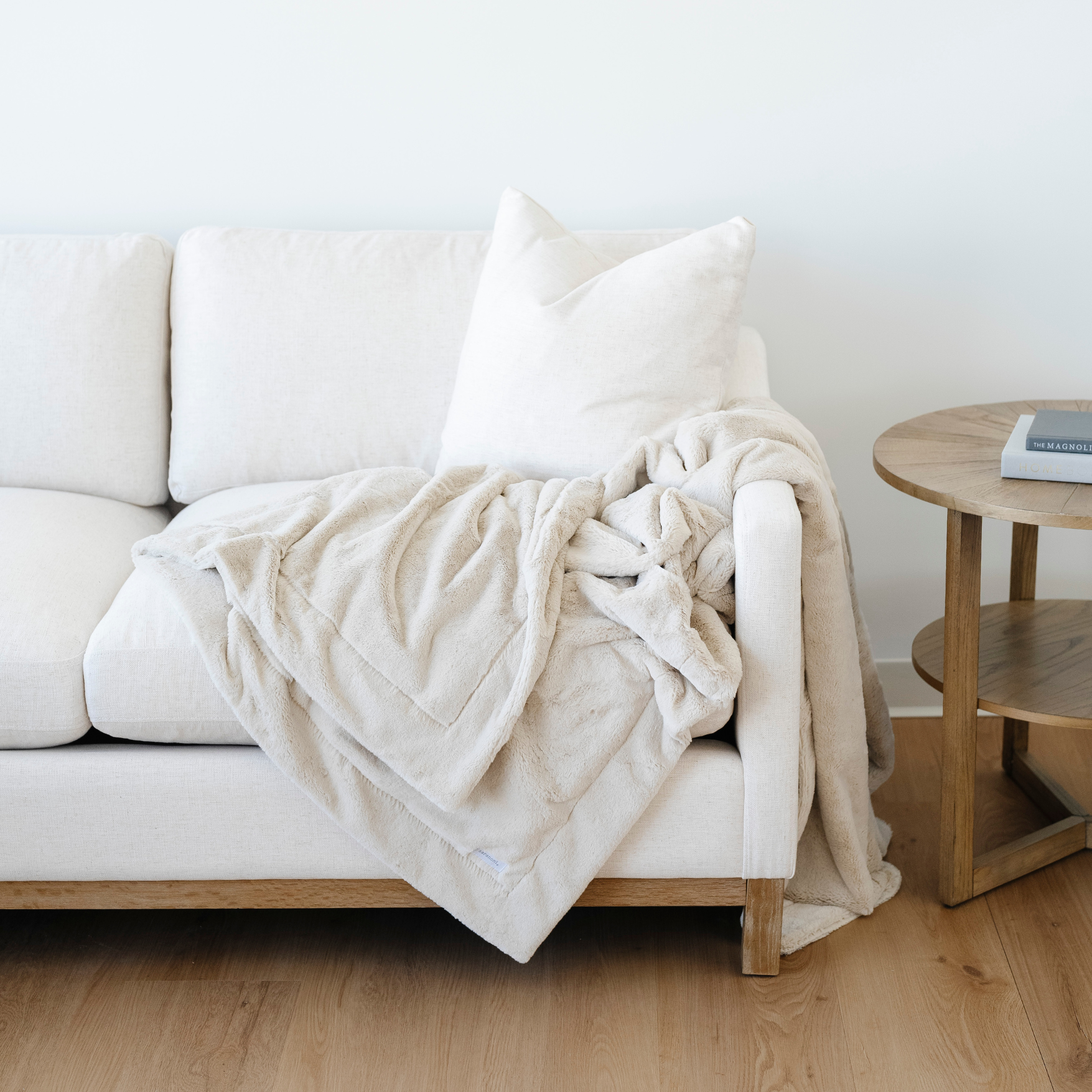 A cream blanket is draped beautifully on a couch. This lush blanket is a luxury blanket and a Saranoni blanket. Enjoy this extra large blanket as a home decor staple, as a comfort gift, or for relaxation. Embrace luxury that lasts with this soft blanket. 