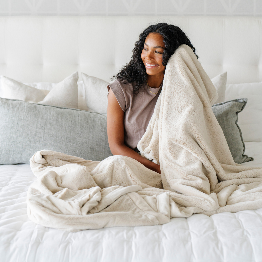 A woman holds a Buttermilk Lush XL Saranoni blanket, designed for oversized comfort and featuring a buttery soft, plush texture. This luxurious Saranoni blanket is perfect for cozy evenings, reading, or home decor. The Saranoni blanket adds warmth, style, and unmatched softness, making it an ideal gift or essential for ultimate relaxation.