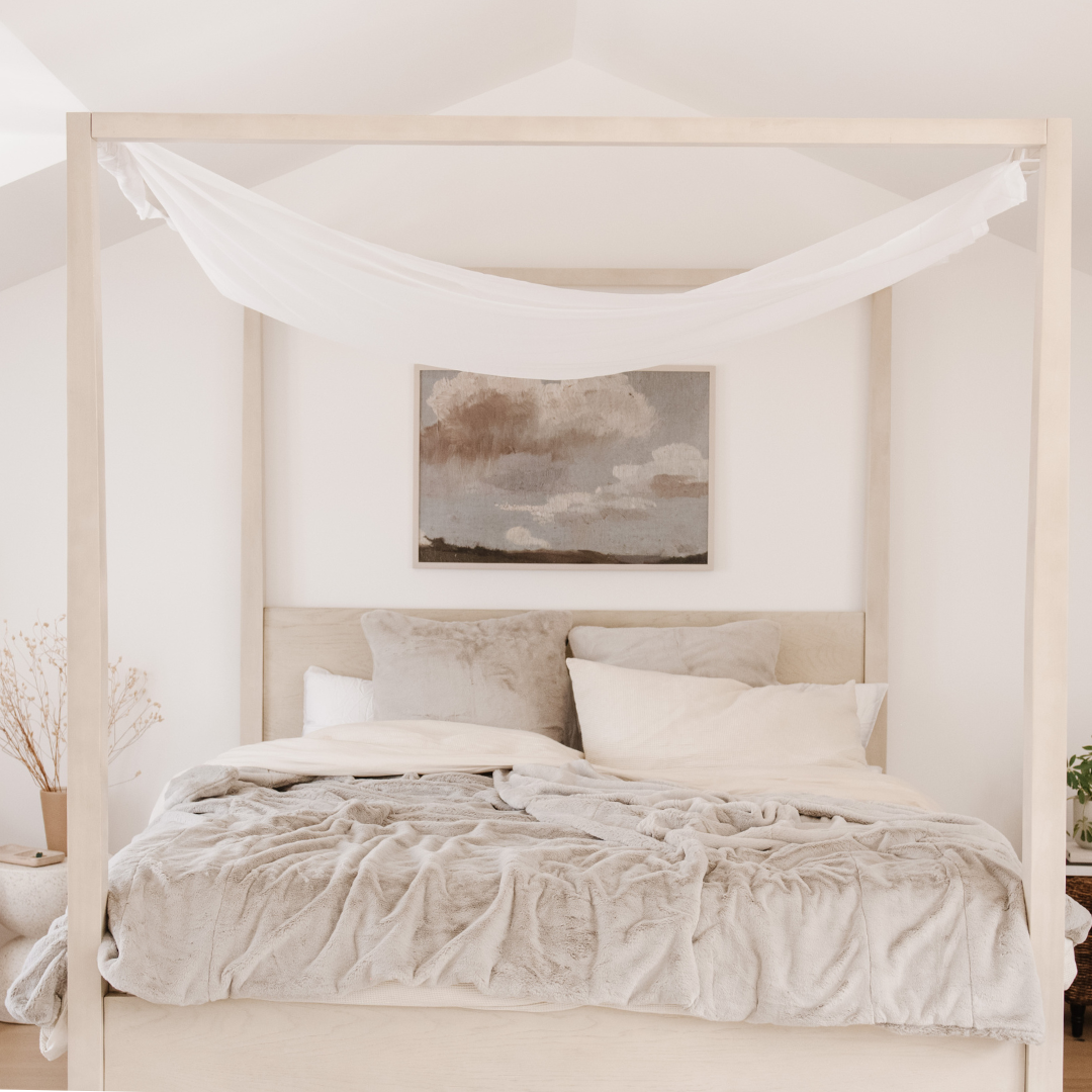 On a bed is a Saranoni Grand Faux Fur blanket, featuring an elegant light cream/gray tone and luxuriously soft texture. This cozy, queen-sized blanket and faux fur blanket offers soothing weight, premium softness, timeless comfort, and is a soft blanket. Perfect as a big blanket and luxury blanket for snuggling or as a luxury bedroom accent, this Saranoni blanket elevates every cozy moment and is a cozy blanket.