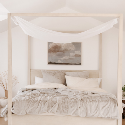 On a bed is a Saranoni Grand Faux Fur blanket, featuring an elegant light cream/gray tone and luxuriously soft texture. This cozy, queen-sized blanket and faux fur blanket offers soothing weight, premium softness, timeless comfort, and is a soft blanket. Perfect as a big blanket and luxury blanket for snuggling or as a luxury bedroom accent, this Saranoni blanket elevates every cozy moment and is a cozy blanket.