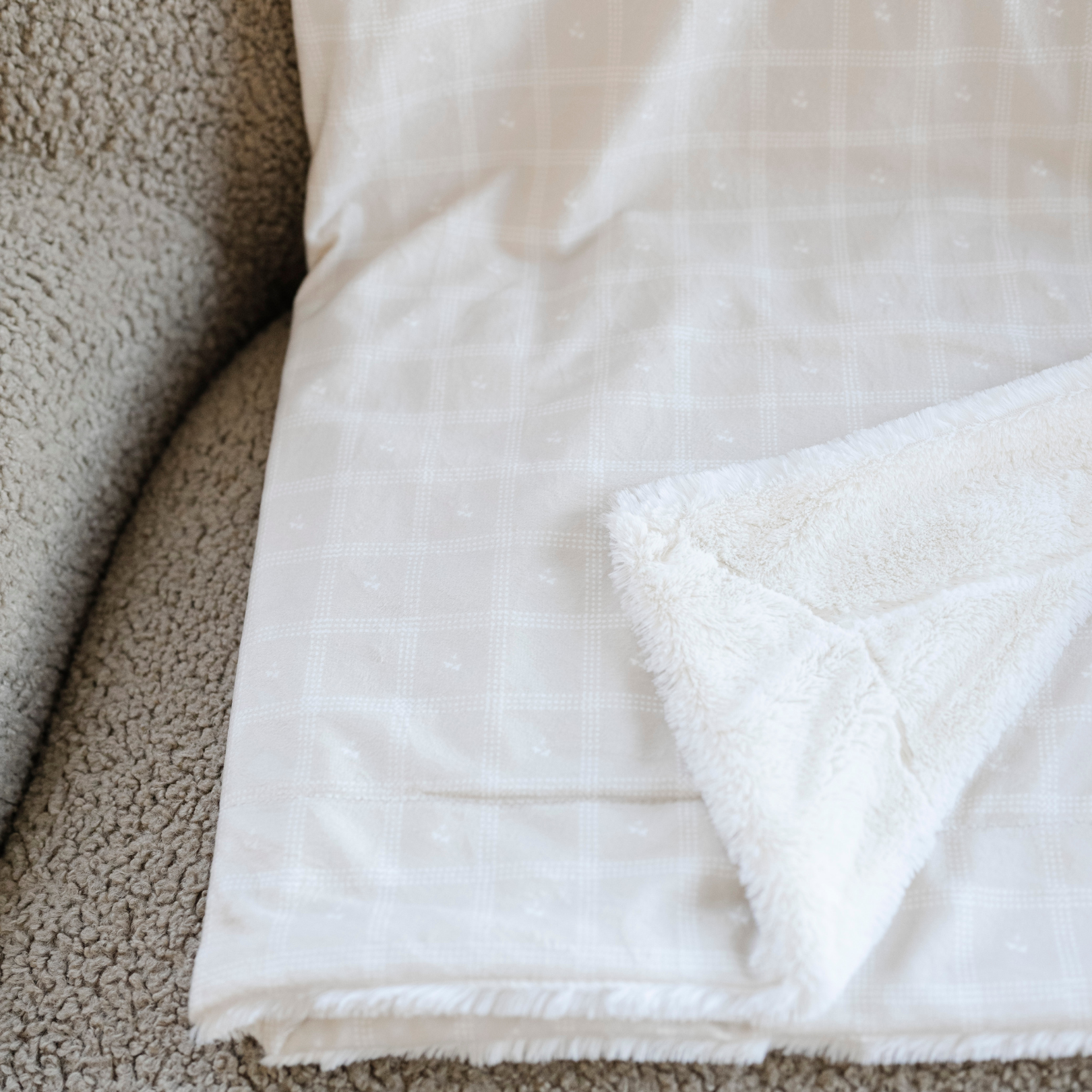 An up-close photo of a luxuriously soft Saranoni minky/lush blanket. This premium dual-textured throw features Saranoni’s signature cream lush fabric on one side and ultra-soft square printed minky on the other. Designed for ultimate relaxation, this plush blanket is perfect for snuggling, movie nights, and adding a touch of luxury to any home. This soft blanket is a luxury blanket and a Saranoni blanket. The cozy blanket is a perfect comfort item and a comfortable blanket. 