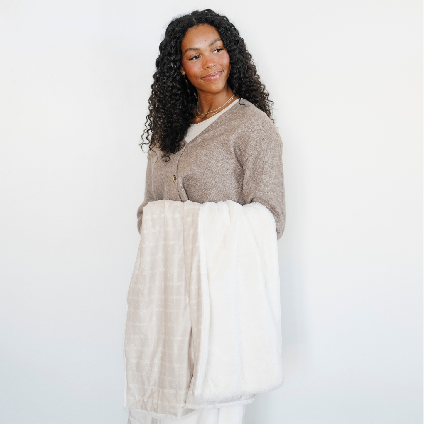 A woman holds a luxuriously soft Saranoni minky/lush blanket. This premium dual-textured throw features Saranoni’s signature cream lush fabric on one side and ultra-soft square printed minky on the other. Designed for ultimate relaxation, this plush blanket is perfect for snuggling, movie nights, and adding a touch of luxury to any home. This soft blanket is a luxury blanket and a Saranoni blanket. The cozy blanket is a perfect comfort item and a comfortable blanket. 