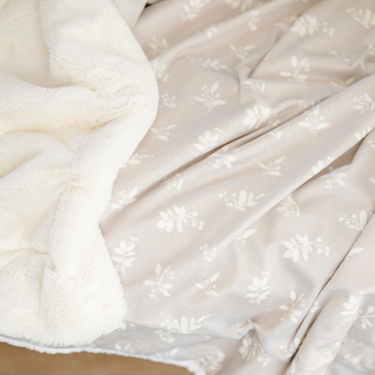 An up-close photo of a soft Saranoni minky/lush blanket. This extra-large throw blanket features Saranoni’s signature cream lush fabric on one side and ultra-soft floral printed minky on the other. Designed for ultimate relaxation, this high-quality, plush blanket is perfect for snuggling, movie nights, and adding a touch of luxury to any home. This soft blanket is a luxury blanket and a Saranoni blanket. The cozy blanket is a perfect comfort gift and is also beautiful for home decor. 