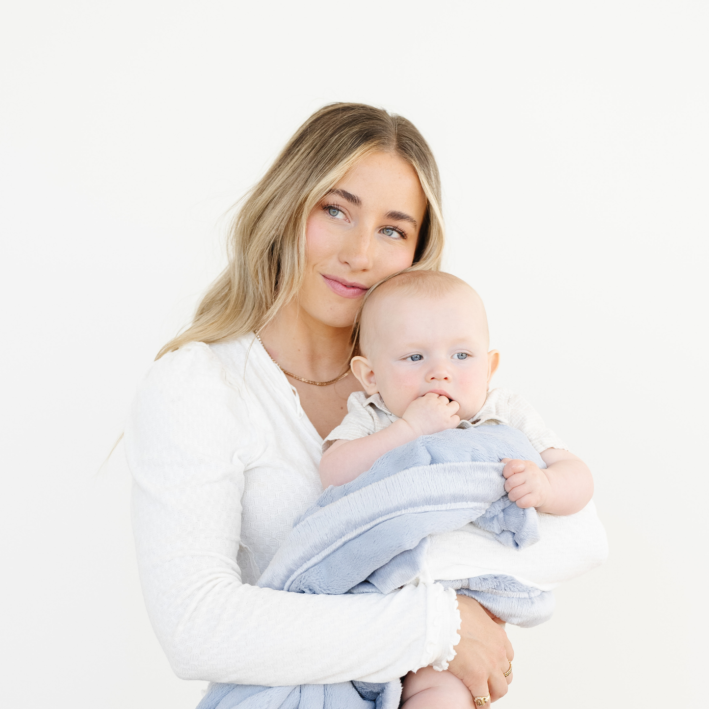 Mom holds baby boy snuggled with Storm Cloud Lush Mini blanket. 