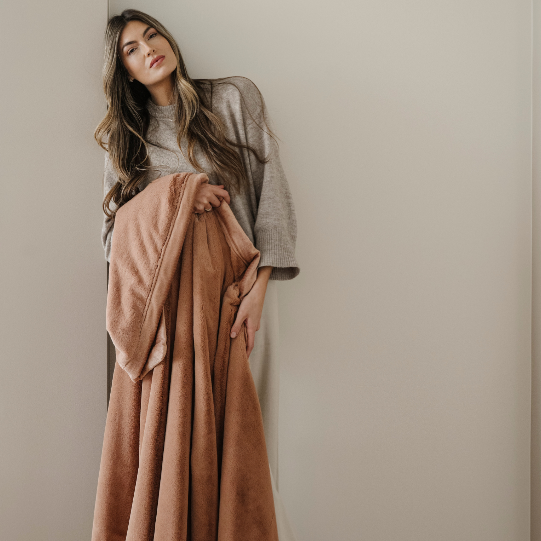 A woman holds a dark peach lush blanket. This soft blanket is a luxury blanket and a Saranoni blanket. This blanket's buttery-soft texture makes it perfect for gifting, relaxing, and using for home decor. Enjoy this cozy blanket for years to come!