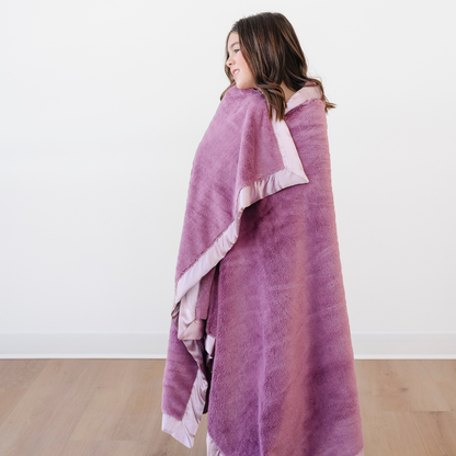 A little girl is wrapped in a lush purple blanket that is a toddler blanket. This soft blanket is a luxury blanket and a Saranoni blanket. This cute blanket is a great as toddler gift or little girl gift. 
