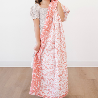 A little girl holds a pink and white bamboo rayon muslin quilt that has a woodland animal pattern on it. This soft blanket is a Saranoni blanket and is a great kids blanket. Since the fabric gets softer with every wash it is a great baby gift or toddler gift. 