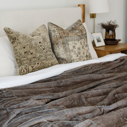 On a bed is a Saranoni Grand Faux Fur blanket, featuring an elegant light brown tone and luxuriously soft texture. This cozy, queen-sized blanket and faux fur blanket offers soothing weight, premium softness, timeless comfort, and is a soft blanket. Perfect as a big blanket and luxury blanket for snuggling or as a luxury bedroom accent, this Saranoni blanket elevates every cozy moment and is a cozy blanket.