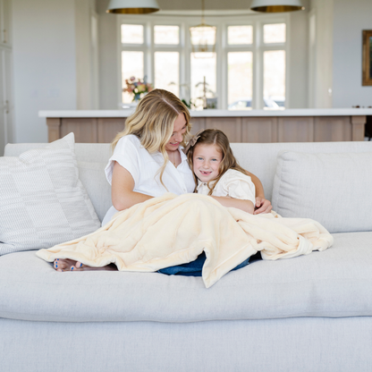 A mother and daughter sit with a Toddler Chiffon (light yellow) Colored Lush Luxury Saranoni Blanket. The soft blanket is a baby blanket or toddler blanket.