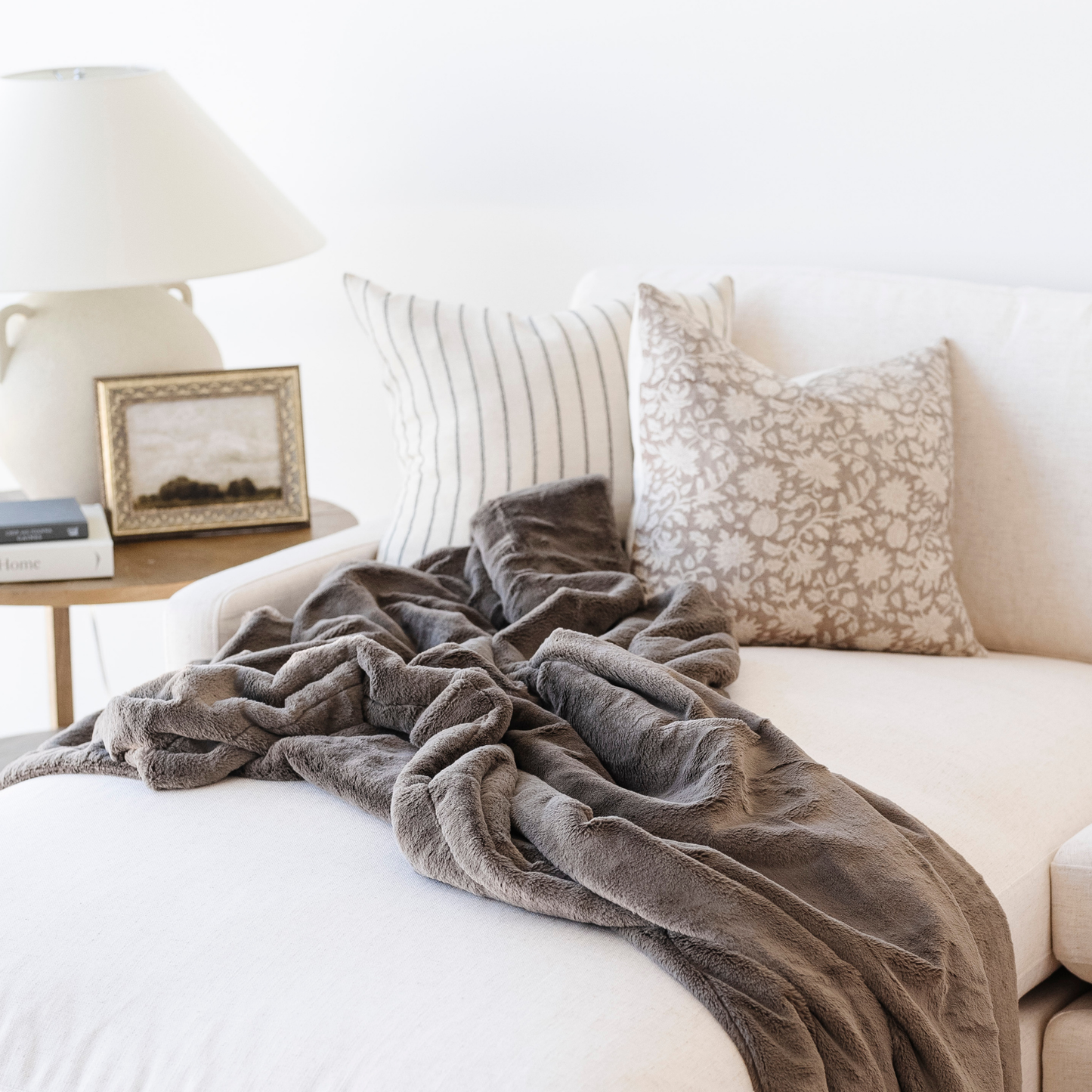 A brown blanket is beautifully draped on a couch. This soft blanket is a lush Saranoni blanket and a luxury blanket. This blanket is great for relaxation, gifting, or as a home decor item. 