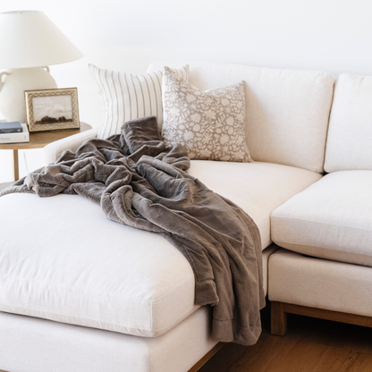 A brown lush blanket that is a Saranoni blanket is beautifully draped on a couch. This soft blanket is a luxury blanket and a faux fur blanket. Use this cozy blanket for gifting, relaxing, or as a home decor staple. Enjoy this extra large blanket for years to come. 