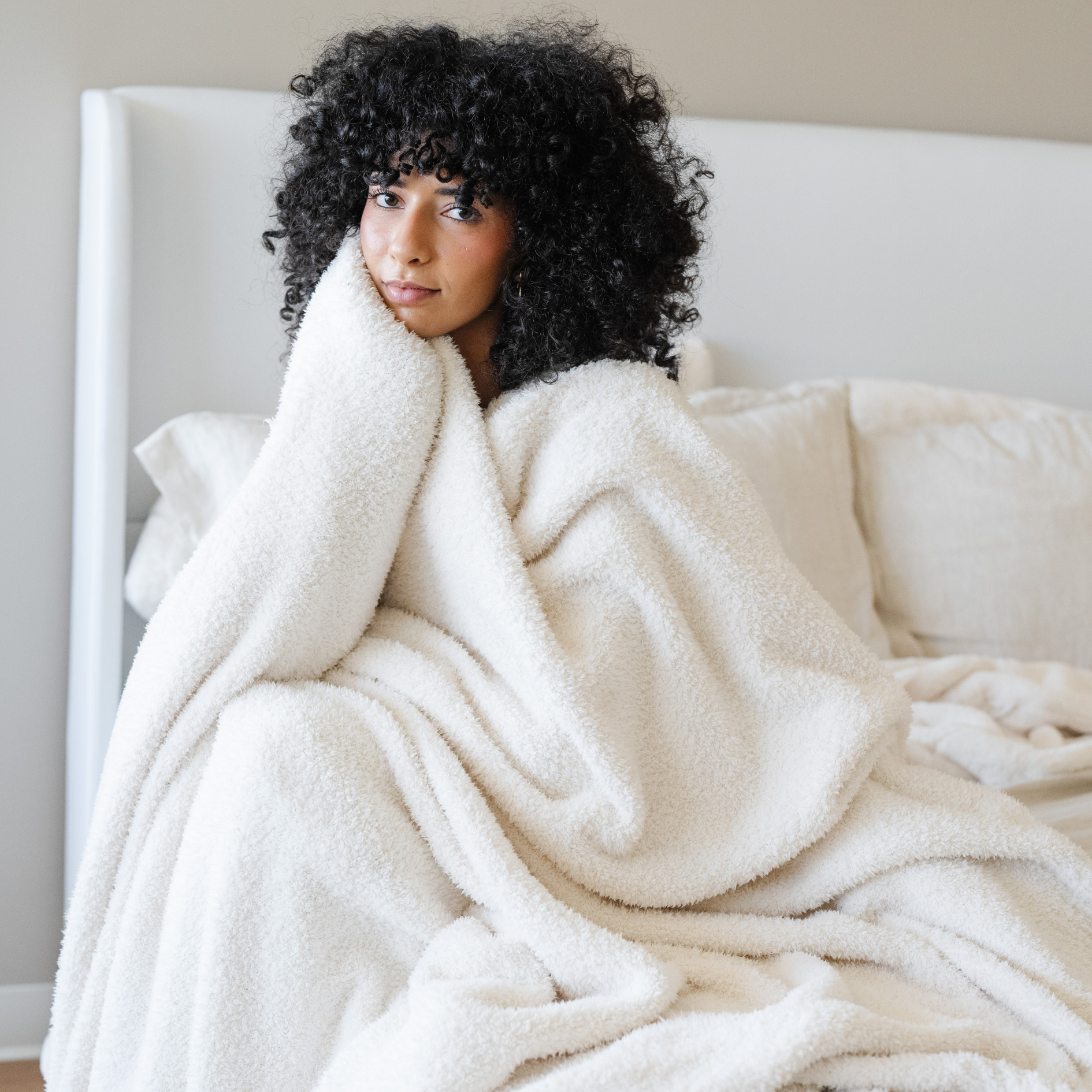 Woman wrapped in Ivory Bamboni XL cozy blanket. 