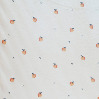 Close-up of Minky Stretch Luxe fabric in a delicate apple pattern. Made from 94% polyester and 6% spandex, this ultra-soft, stretchy fabric is perfect for baby essentials like swaddles, changing pad covers, and crib sheets.