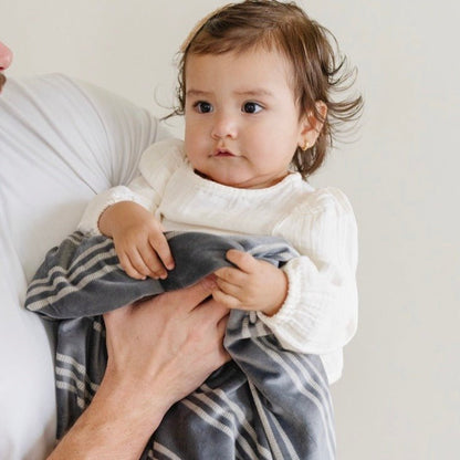Baby holding on to blue and white striped MINKY STRETCH RECEIVING BLANKETS - Saranoni