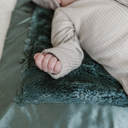 Cozy mini blanket with a plush texture and a delicate satin border, offering warmth and a touch of luxury in a compact size.