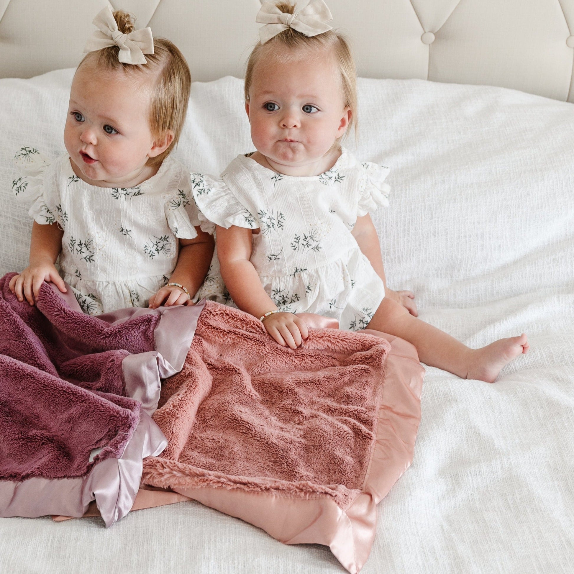 Infant girls laying with beautiful satin border mini blankets.