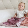 A baby lays under her silky soft, faux fur blanket with satin border.