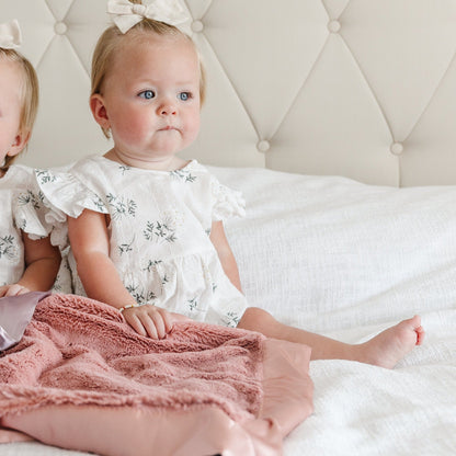 Comforting mini blanket with a satin border, offering a cozy, warm feel with an elegant, silky edge for added sophistication.