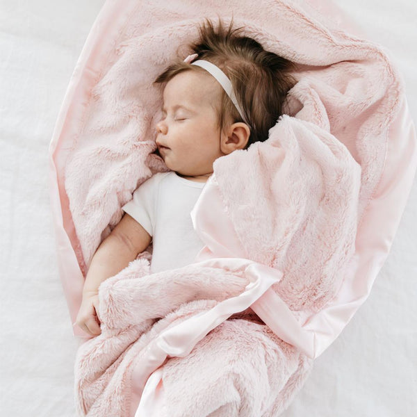 Cute baby girl takes a nap with her favorite pink security lush blanket. 