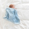 Baby boy cuddled underneath a light blue baby blanket with luxurious satin border.