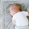 A baby laying on its stomach cuddles with a customizable embroidery blanket for babies.
