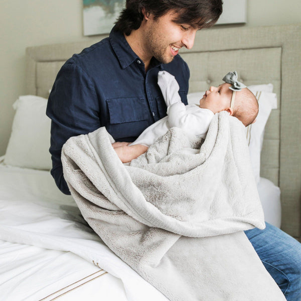 A father cradles his little baby in a silky soft luxury blanket.
