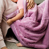 A baby and mom snuggle together with a beautiful purple lush blanket.