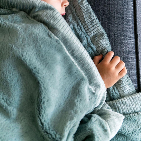 Toddler snuggles in his beautiful Saranoni lush eucalyptus toddler blanket.