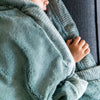 Toddler snuggles in his beautiful Saranoni lush eucalyptus toddler blanket.
