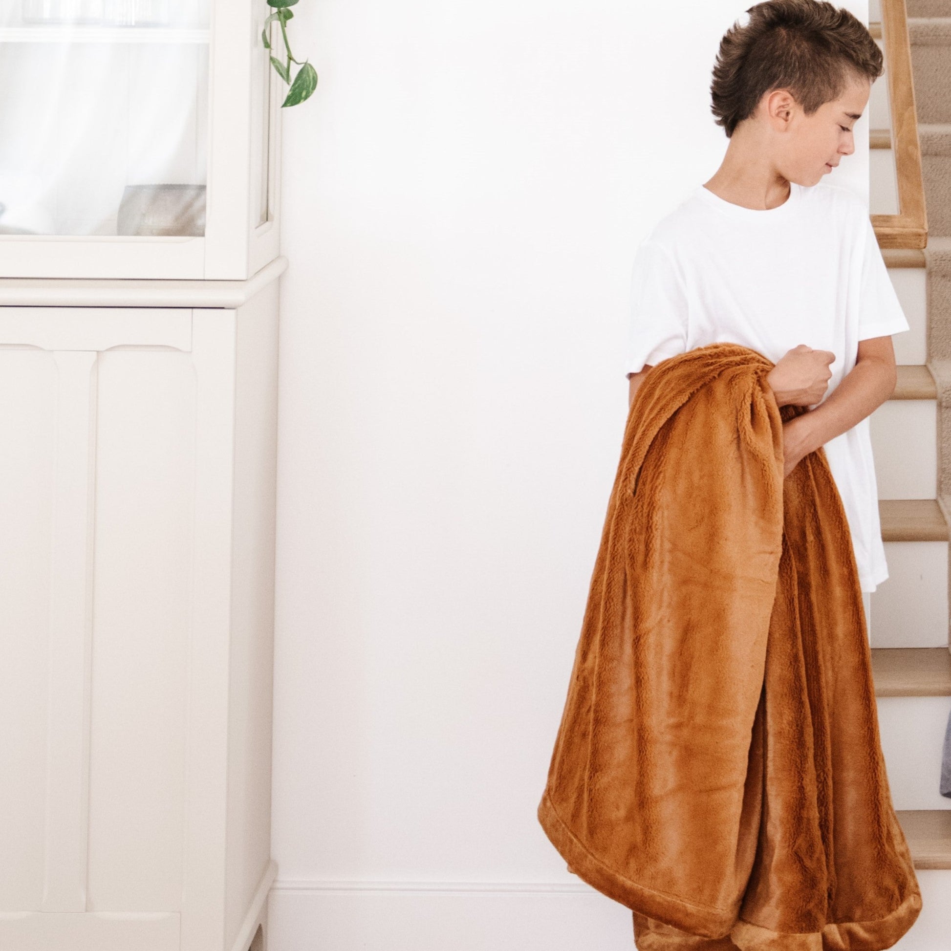 A boy holds a Luxury Toddler Camel (light yellowish brown) Colored Lush Saranoni Blanket. The soft blanket is a toddler blanket or baby blanket.
