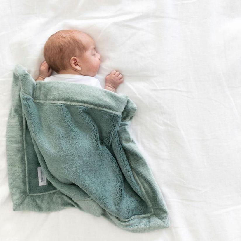 A newborn sleeps under a Eucalyptus colored Lush Saranoni Blanket. The soft blanket is a small blanket and a baby blanket.