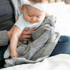 Baby plays on mother's lap with a velvety soft gray baby blanket.