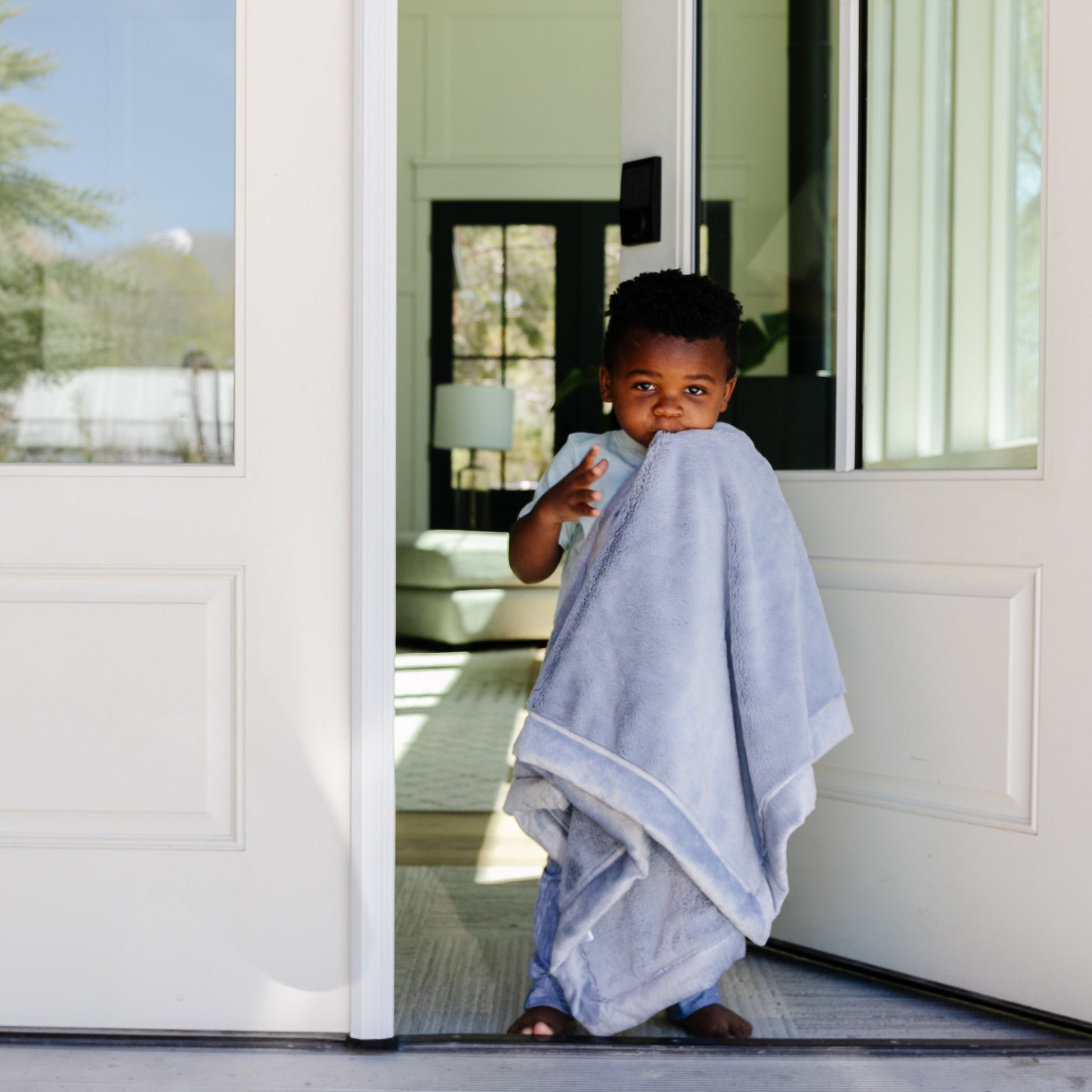 A little boy carries a Luxury Receiving Storm Cloud (dusty blue gray) Colored Lush Saranoni Blanket. The soft blanket is a small blanket and a baby blanket or toddler blanket.