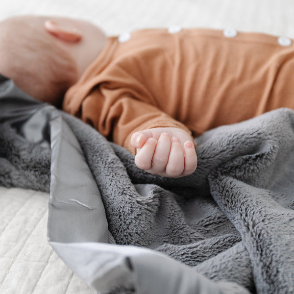 A baby boy lays on a gorgeous Saranoni blanket for babies and toddlers.
