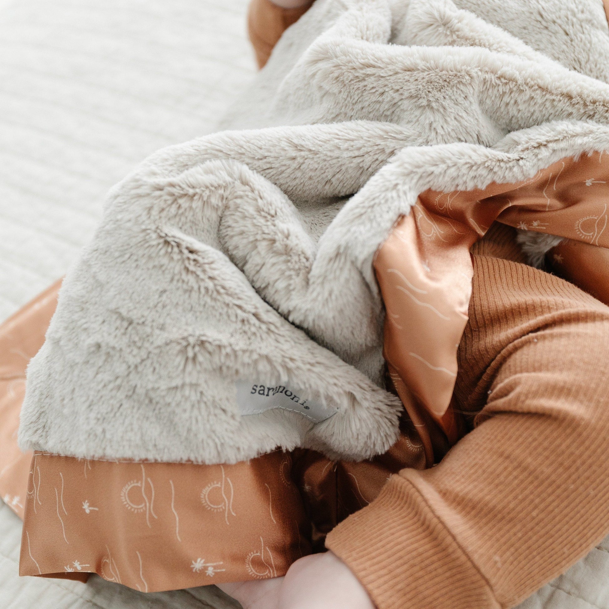 Compact mini blanket with a rich, velvety surface and a satin border, perfect for wrapping in warmth and elegance.