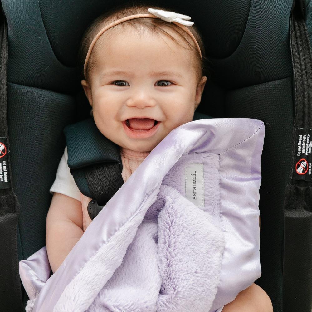 Light purple mini blanket with a velvety surface and a sleek satin border, designed to combine warmth with a sophisticated, silky finish.