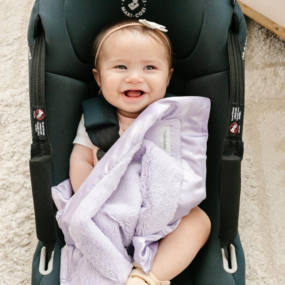 Baby with a light purple mini blanket with a satin border, offering a cozy, warm feel with an elegant, silky edge for added sophistication.