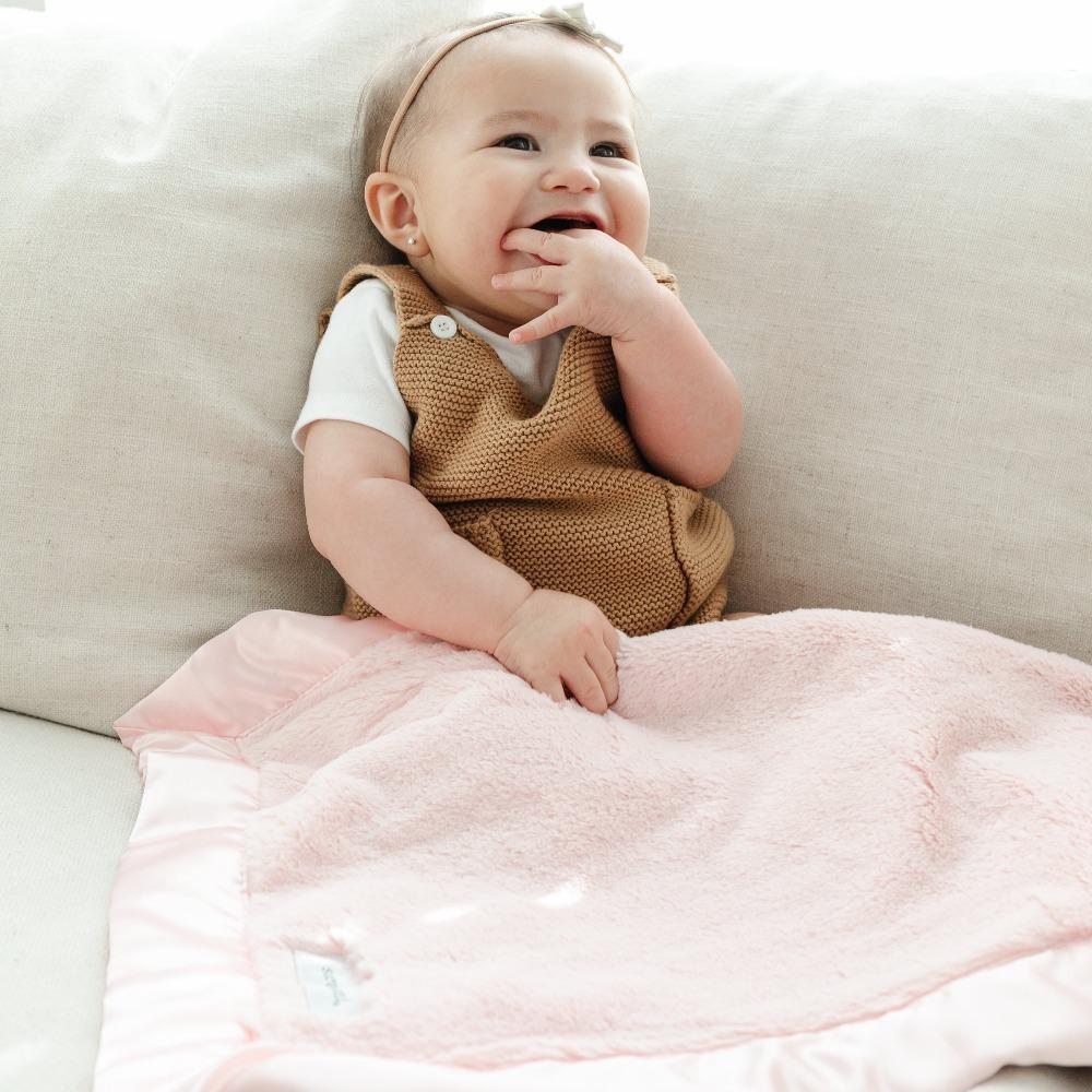 Baby laying with a comforting mini blanket with a satin border, offering a cozy, warm feel with an elegant, silky edge for added sophistication.