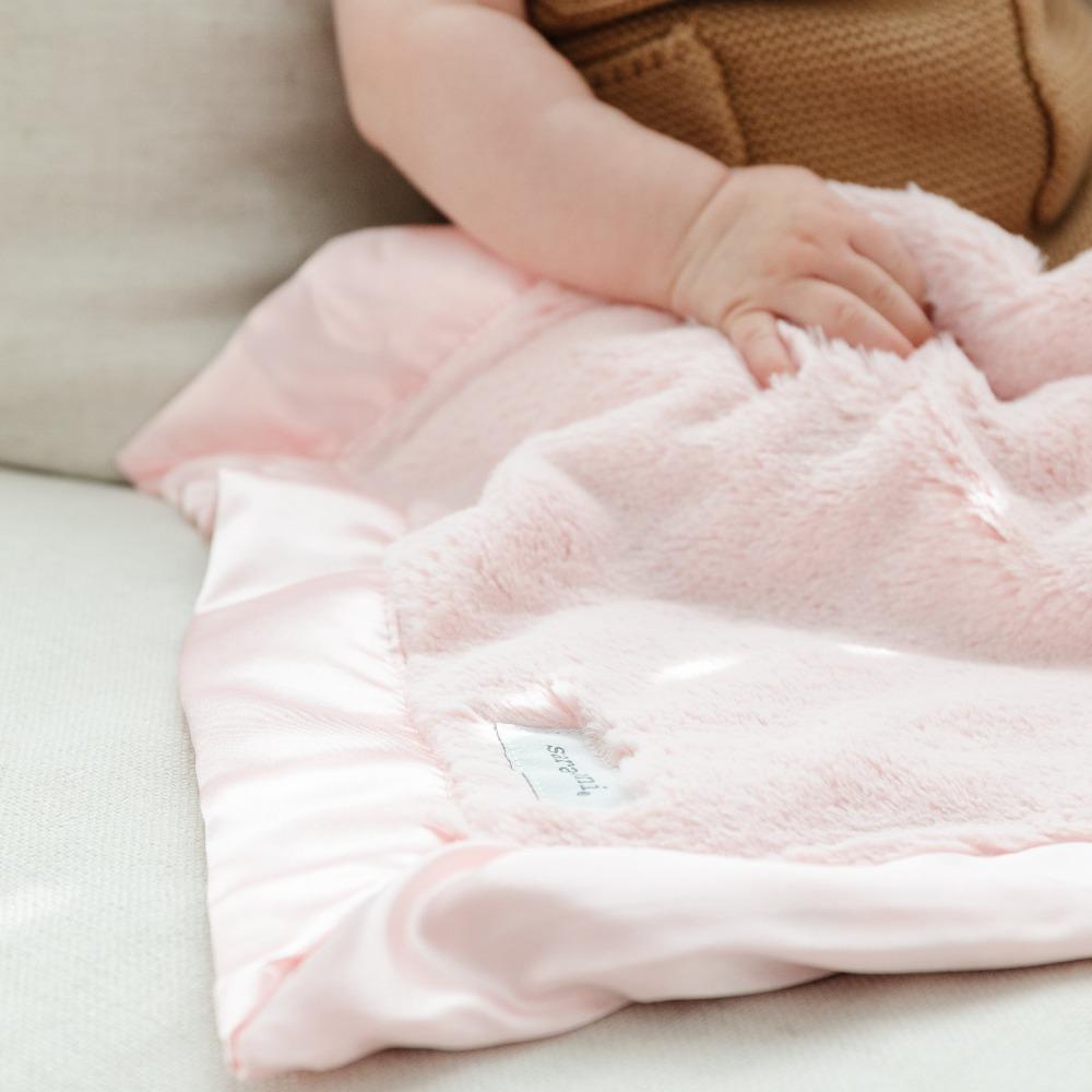 Detailed elegance of a cozy light pink satin bordered mini blanket. 