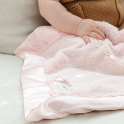 Detailed elegance of a cozy light pink satin bordered mini blanket. 