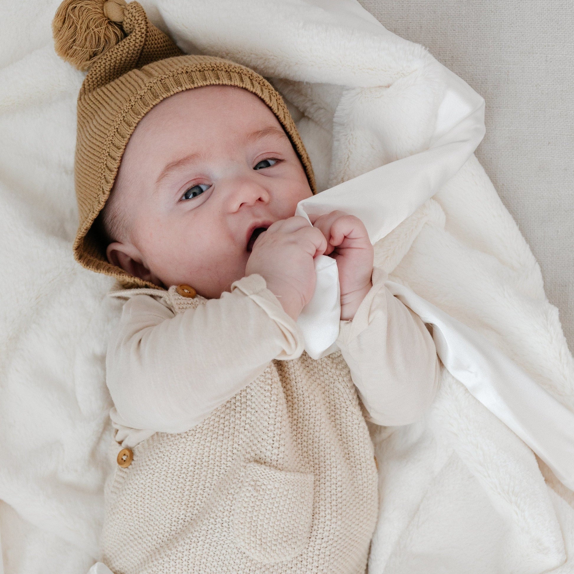 Baby snuggling with a cozy and soft, white satin border mini blanket. 